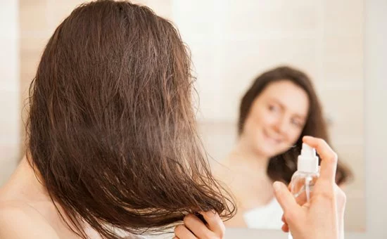Девушка распыляет на волосы парфюмерную дымку